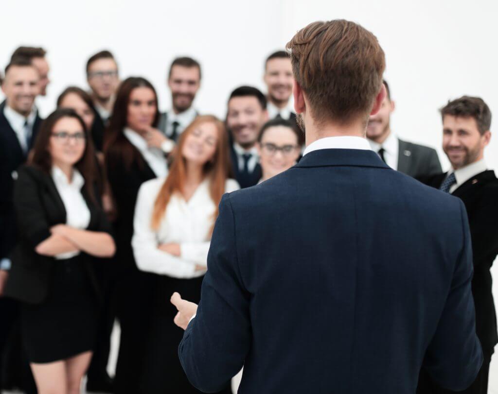 businessman makes a speech to his large business team